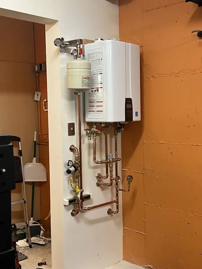 Plumbing technician inspecting water heater connections in Merchantville